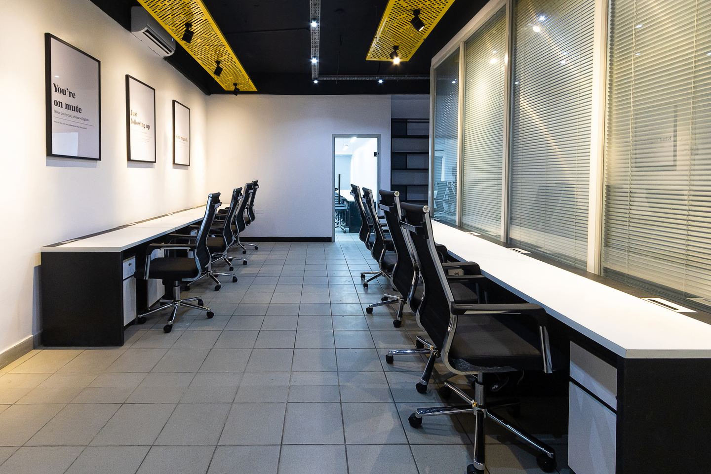 A long desk run facing the glazed offices, framed prints along the wall