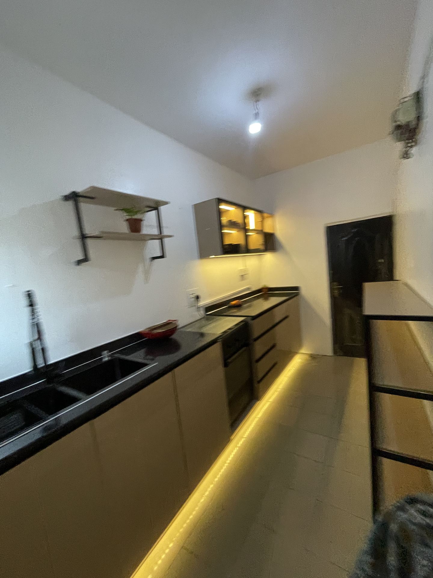 Long galley kitchen with warm toe-kick lighting and black worktops