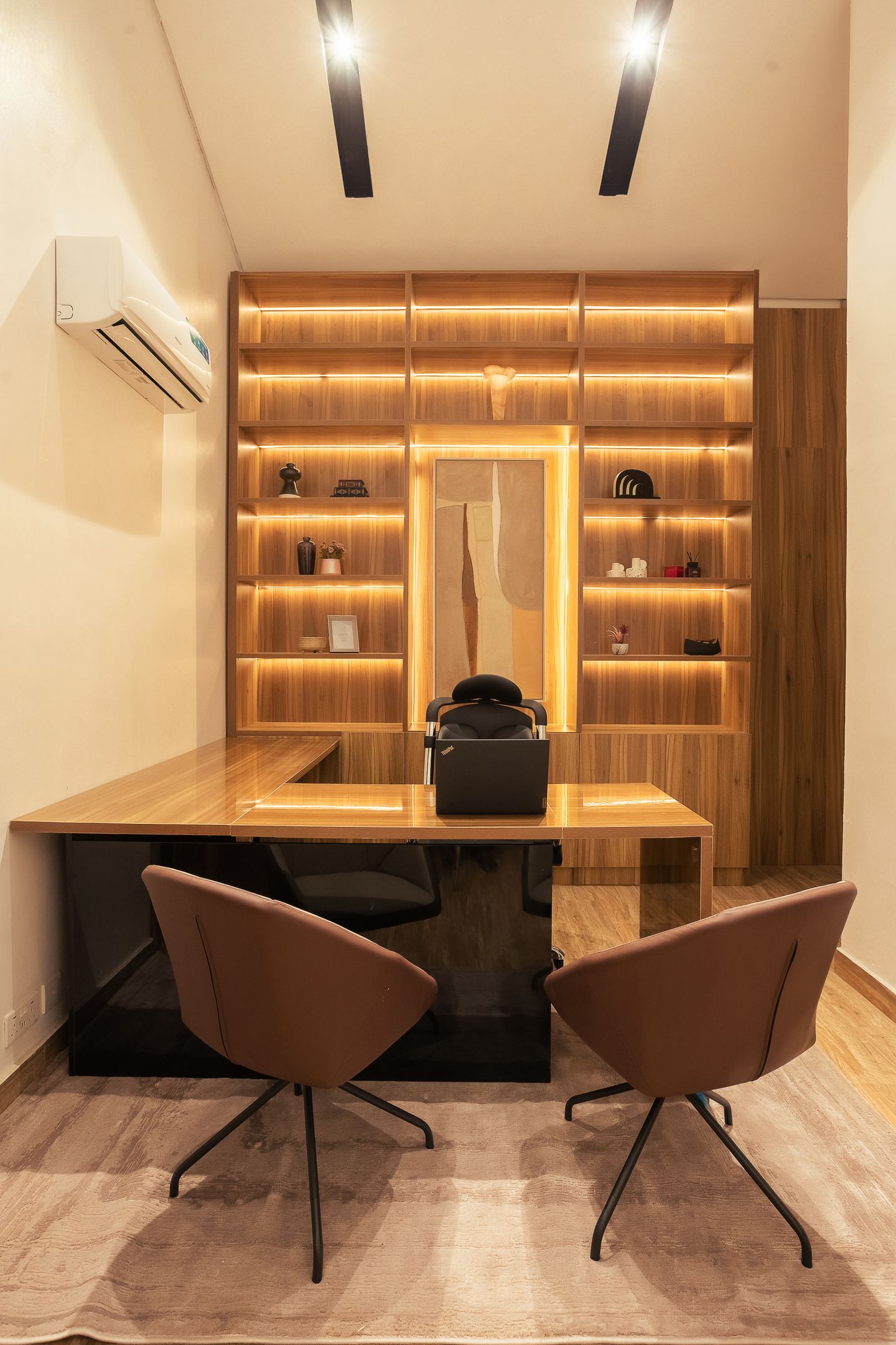 The study, its timber shelving lit from within behind the desk