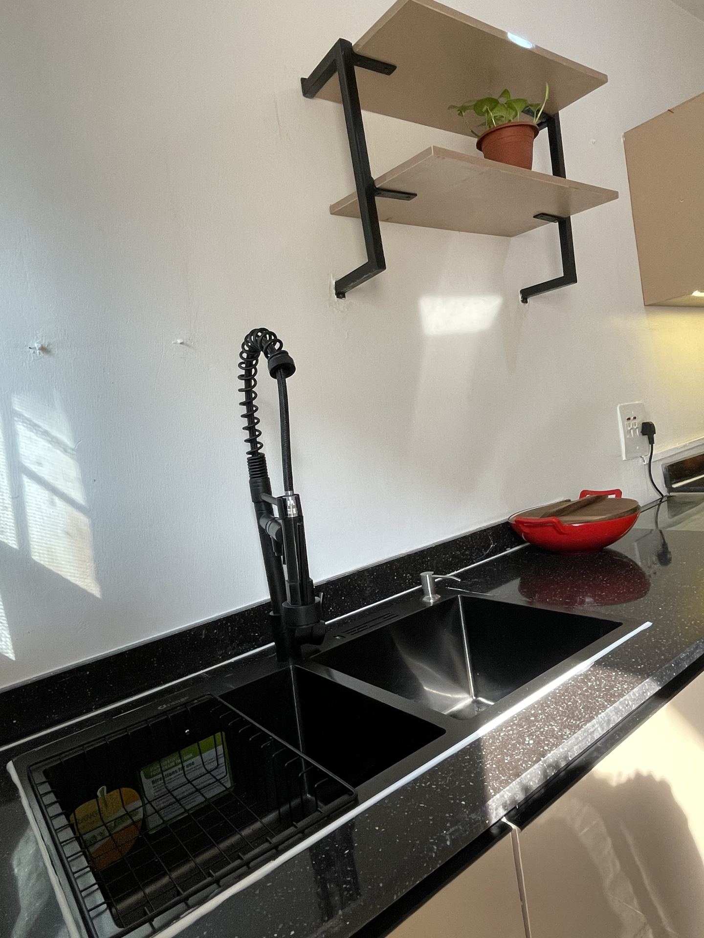 Black double-bowl sink beneath compact open wall shelving