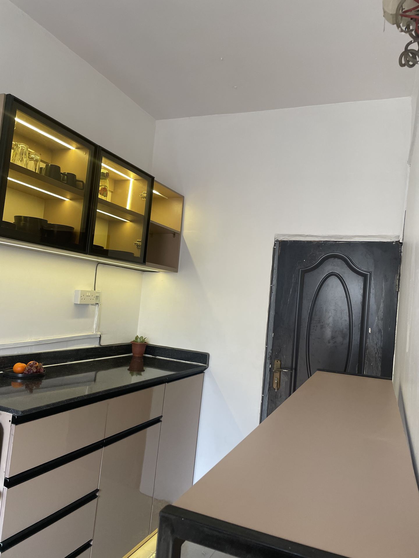 Compact kitchen with lit glass cabinets, black worktop and central island
