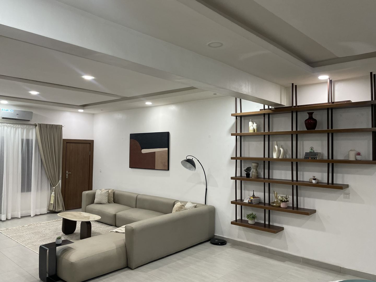 Wide corner view of the completed living room with sectional sofa and shelving