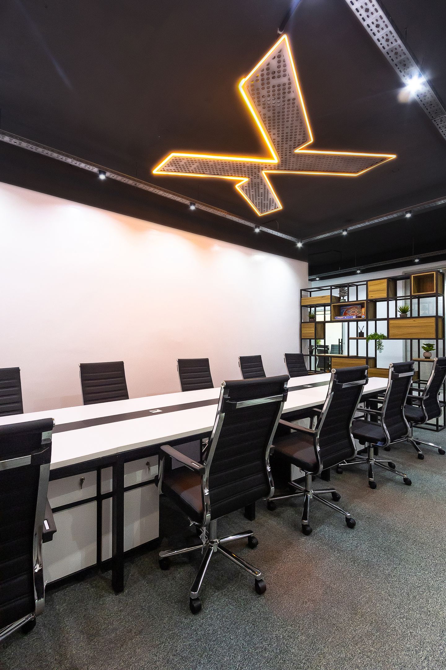 The boardroom's lit ceiling mark, seen down the length of the table