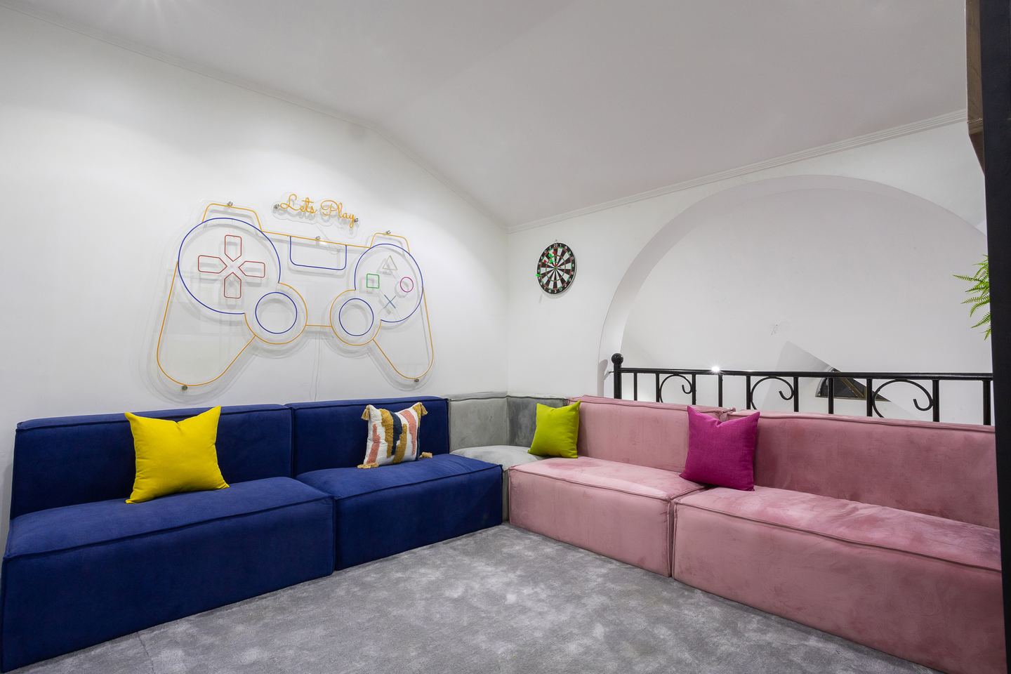 Colour-blocked lounge seating beneath neon game artwork at Novac