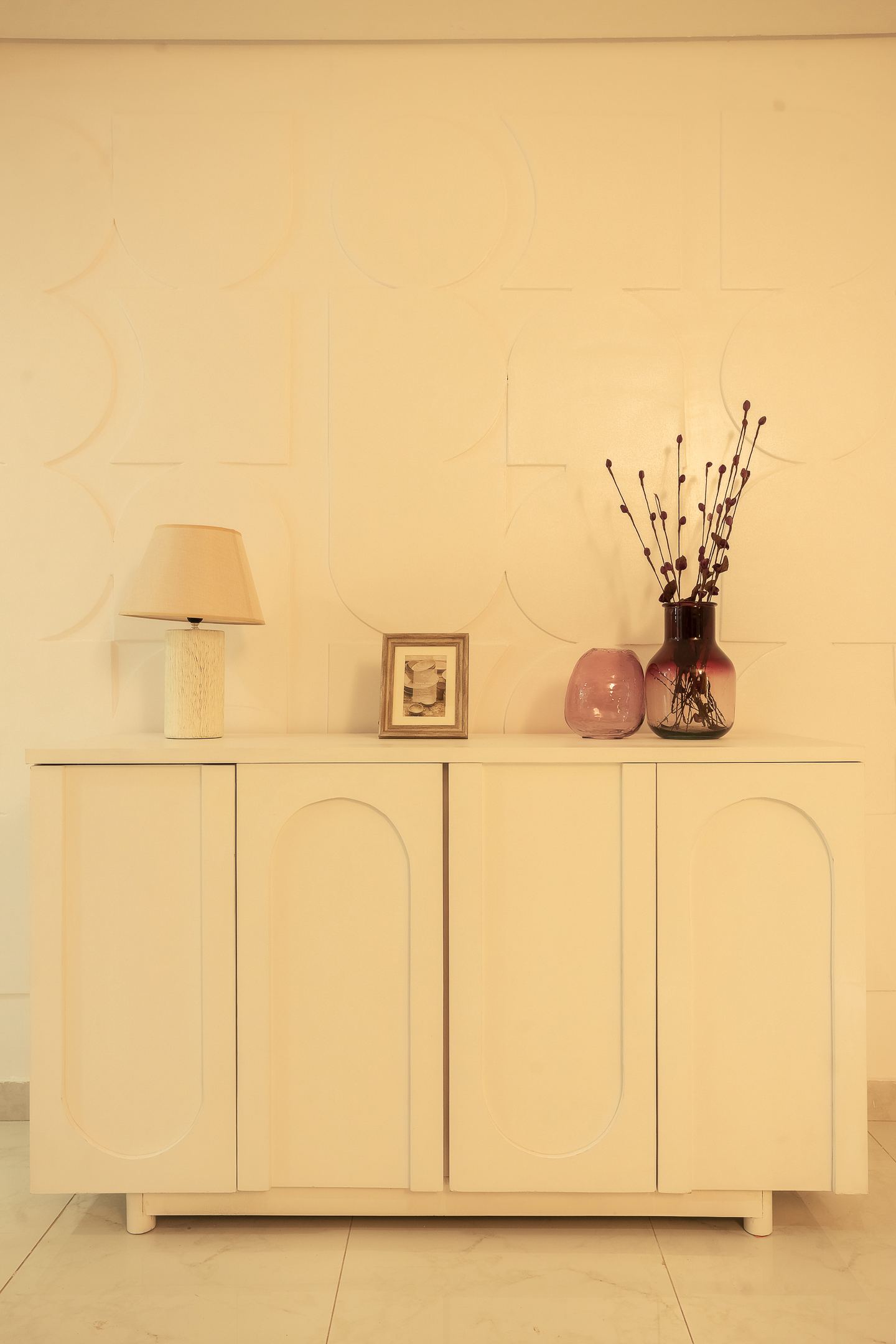 A console dressed with a lamp, a framed picture and dried stems