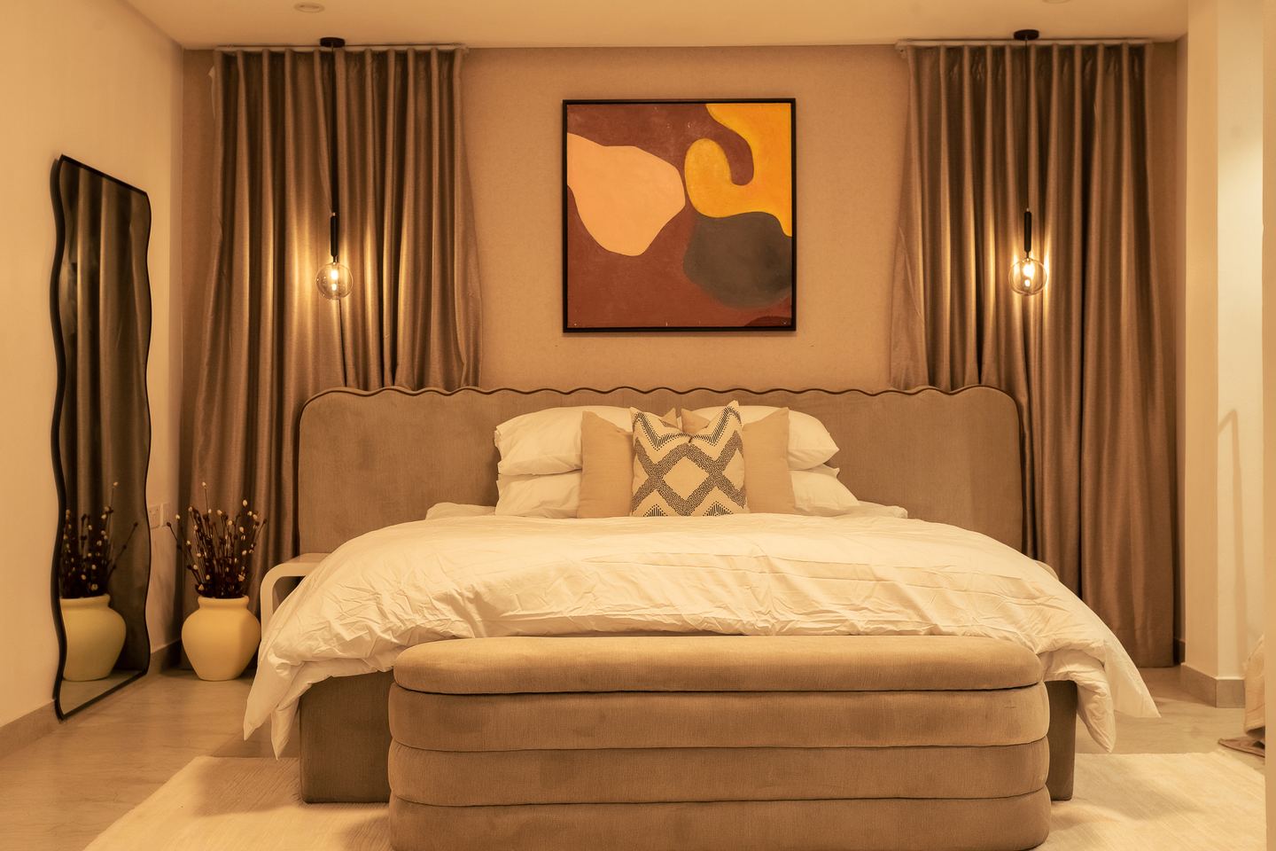 A bedroom with a framed canvas above the bed and a wall light on either side