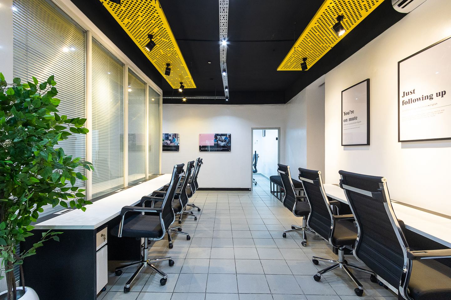 Open-plan desks under yellow acoustic rafts, Nomba Ikeja