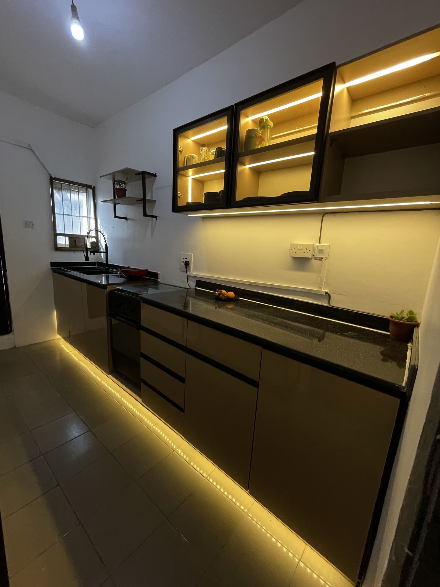 Kitchen worktop framed by illuminated wall cabinets and black drawers