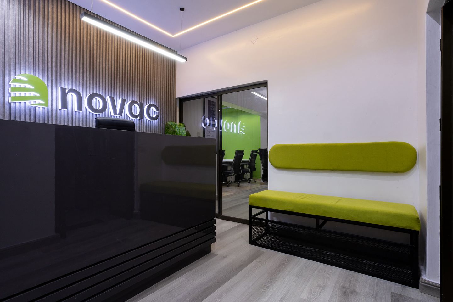 Green upholstered waiting bench beside a glazed Novac meeting room