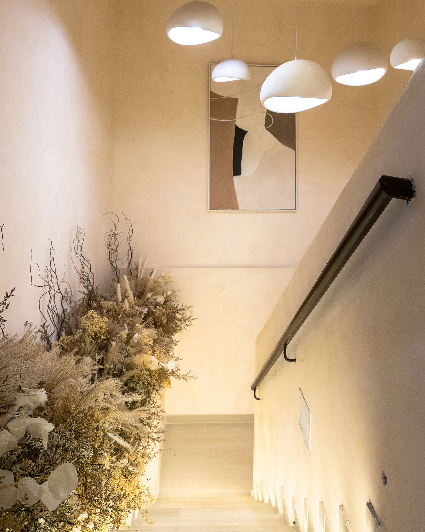Pendant-lit stair landing with dried floral styling at Emagine